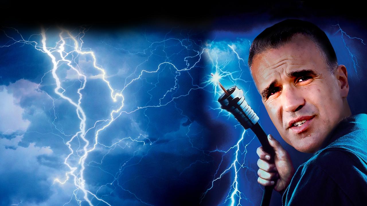 Man in a blue shirt holds a lightning-testing wand as bright bolts fill a stormy sky behind him