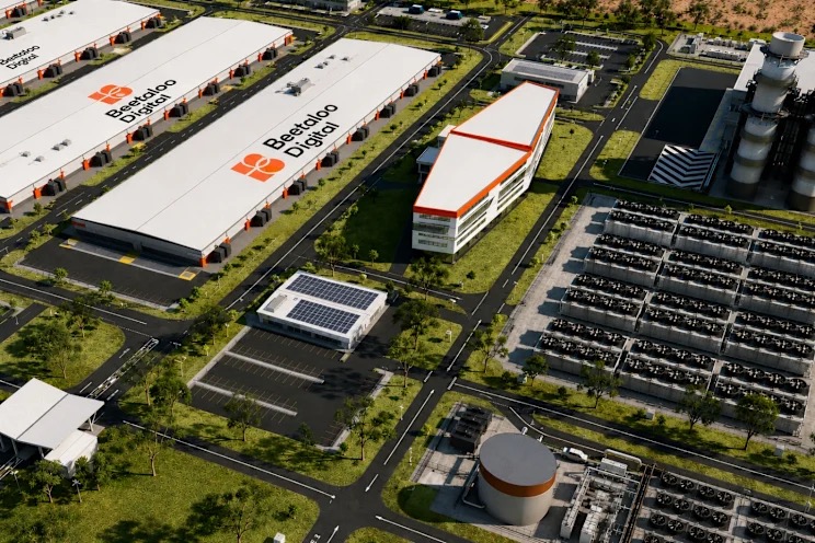 Aerial view of an industrial campus with white warehouses, a red-roofed office building, solar panels, and adjacent parking lots and roads.