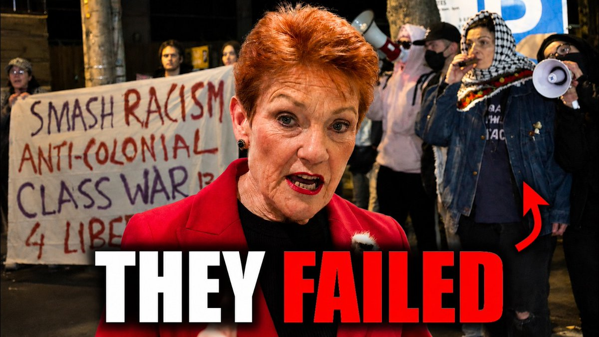 Woman in a red blazer speaks to protesters at night; a banner behind her reads 'SMASH RACISM ANTI-COLONIAL CLASS WAR' among people with megaphones.