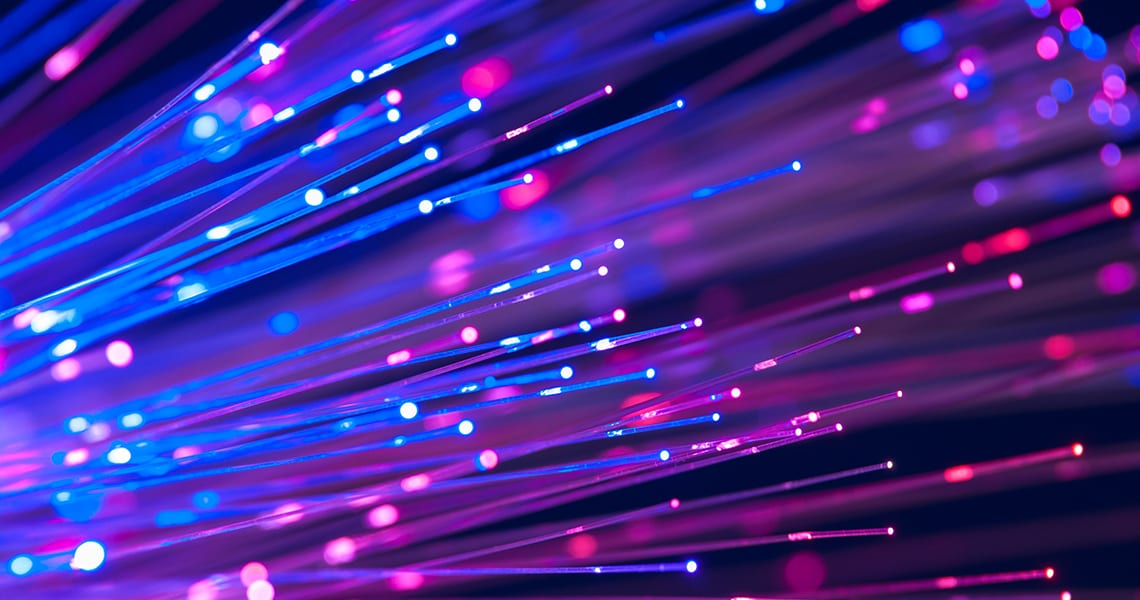 Abstract fiber-optic light streaks in blue and pink, suggesting high-speed connectivity and data transfer (decorative background)